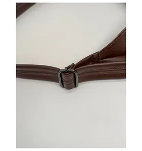 Detail view of the adjustable dark brown leather strap with a metallic buckle on the bag