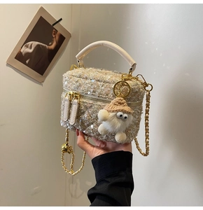 Detail of tweed bucket bag with sequins, gold chain and fuzzy monster charm
