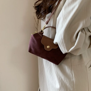 Detail of burgundy suede crossbody bag with brown leather flap on a beige coat