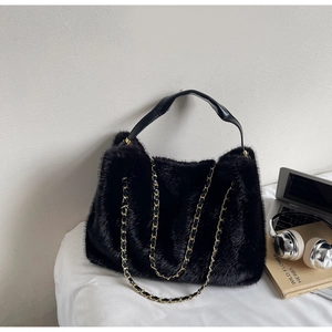 Detail of soft black faux fur tote bag with gold chain strap and elegant leather handle