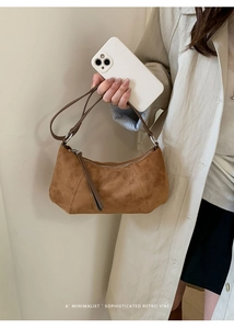 Détail d'un sac bandoulière en daim marron vintage montrant la texture et la sangle