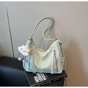 Detail of light green ruched tote bag with decorative zippers and plush cloud charm