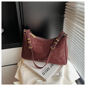 Close-up of a burgundy frosted leather crossbody bag with vintage texture on art books