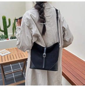 Détail du sac seau noir en patchwork avec texture suédée et boucle métallique sur la sangle