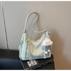 Detail of light green hobo bag featuring tassel zippers and a cloud plush charm