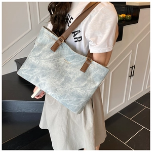 Detail showing the light blue textured tote bag with dark brown leather straps