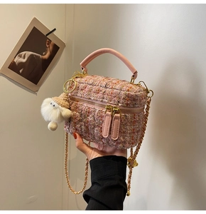 Detailed macro of pink tweed mini bag with gold chain and white plush charm accessory