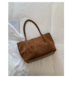Detailed view of brown suede tote bag with soft texture on a white fabric background