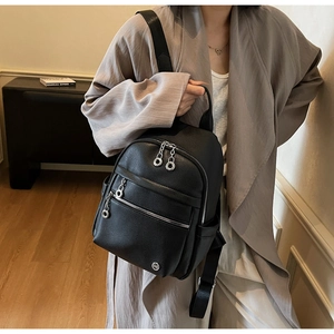 Close-up of black lychee grain leather backpack with silver zippers and side pockets