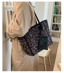Detail view of large leopard print tote bag with black leather straps and mini pouch