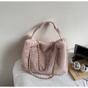 Detail of pink faux fur tote bag with golden chain straps in a cozy home setting