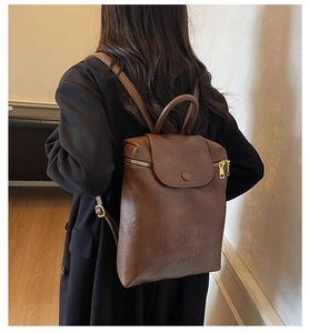 Détail du sac à dos vintage en cuir marron avec bouton pression aimanté et fermeture éclair dorée