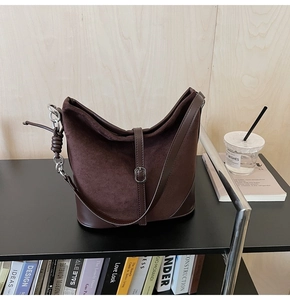 Détail du sac seau en daim marron avec chaîne en métal argenté et décorations tressées