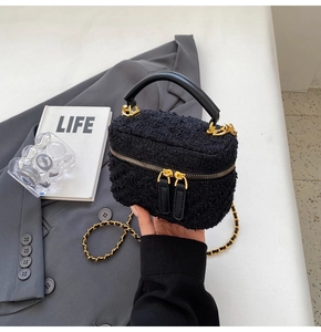 Detail of black tweed bucket bag with golden chain strap and leather handle texture