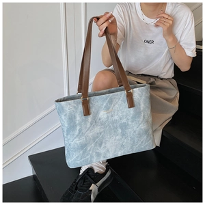 Detail of light blue marble-pattern tote bag with dark brown straps on stairs