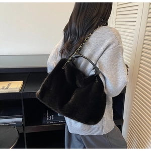 Close-up of black fuzzy faux fur tote bag with gold chain strap and leather handle