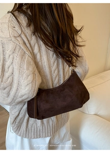 Sac demi-lune en daim marron porté avec un pull en maille beige pour un style rétro