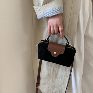 Detail of color-block suede crossbody bag featuring gold hardware and a brown leather flap