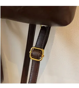 Gros plan sur la bandoulière réglable en cuir marron foncé avec boucle dorée polie
