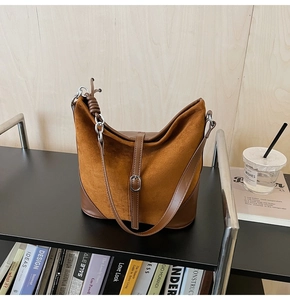 Détail d'un sac seau marron montrant le mélange de daim et cuir avec boucles argentées