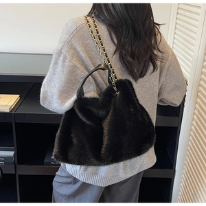 Detail of plush black faux fur tote bag showing metal chain strap and leather handle