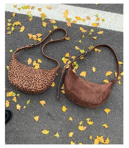Leopard print and brown suede crescent bags on asphalt with autumn ginkgo leaves