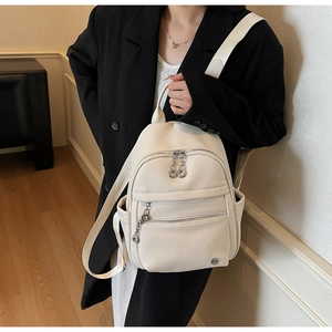 Detail shot of white litchi pattern leather backpack with silver metal zippers and chains