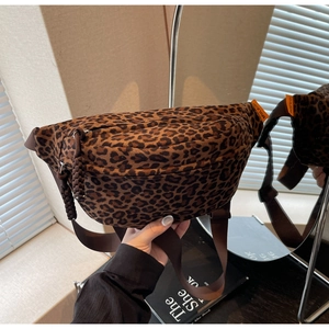 Close-up of leopard print crossbody bag with woven zipper pull and brand label