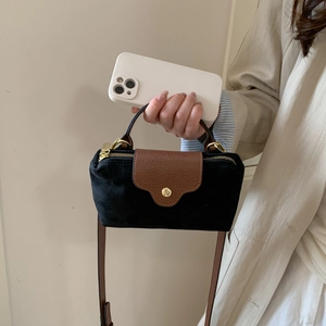 Detail of mini faux suede handbag with black and brown contrast and gold hardware