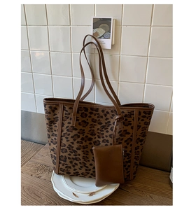 Detail of leopard print tote bag with brown leather straps and matching small pouch