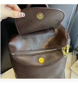 Vue détaillée du sac en cuir marron foncé avec quincaillerie dorée gravée et zip