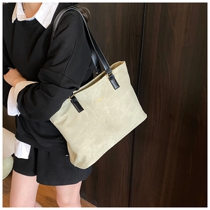 Detail of light beige tote bag with black long straps and gold letter embossing