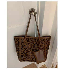 Detail of leopard print tote bag with brown straps and matching small pouch on a door