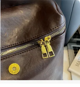 Détails des doubles fermetures éclair dorées et du fermoir magnétique sur un sac à dos en cuir