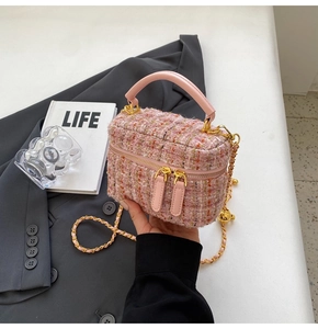 Detail of pink tweed bucket bag with woven texture, leather handle and gold chain strap