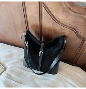 Détail du sac hobo en daim noir montrant la boucle en métal argenté et les textures