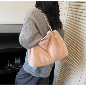 Detailed close-up of pink faux fur tote bag with golden metal chain strap on model