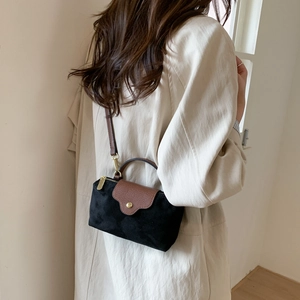 Close-up of contrast suede mini crossbody bag with gold hardware on person model