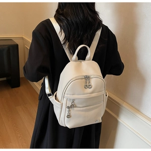 Close-up of creamy white faux leather backpack with silver hardware and logo detail