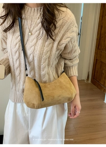 Gros plan d'un sac demi-lune en daim jaune moutarde avec bandoulière noire et long zip