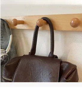 Détail d'un sac à dos en cuir marron avec poignée renforcée et texture de cuir fine