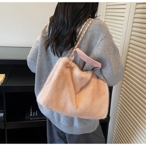 Close-up of pink faux fur tote bag featuring gold chain strap for autumn winter