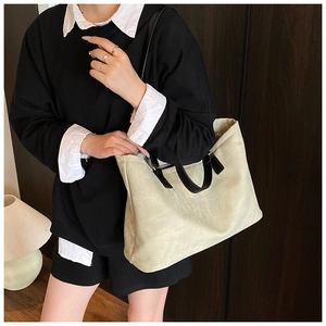 Close-up of beige canvas tote bag with black handles in a lifestyle setting