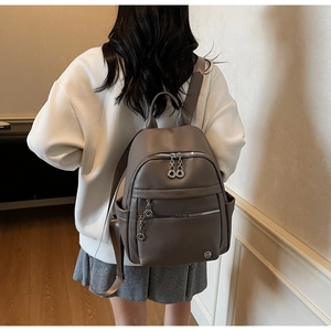 Close-up of grey pebble leather backpack with silver zippers and double ring pulls