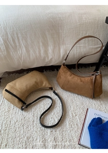 Gros plan de sacs demi-lune en daim rétro marron et beige sur un tapis blanc moelleux