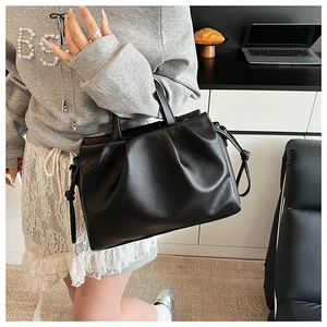 Close-up of black pleated leather tote bag with knotted drawstring and round handle