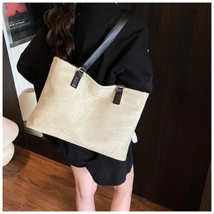 Side view of large beige suede tote bag with black leather straps on a model