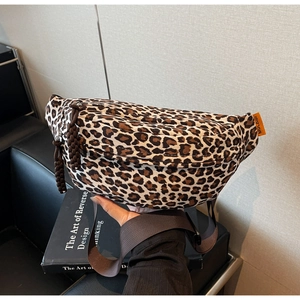 Detailed close-up of leopard print crossbody waist bag with orange logo tag and brown strap