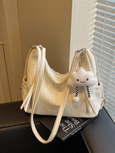 Large cream tote bag with cloud charm and pleated texture on black leather seat