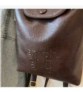 Gros plan sur le sac à dos vintage en cuir PU marron foncé avec relief et boucle dorée